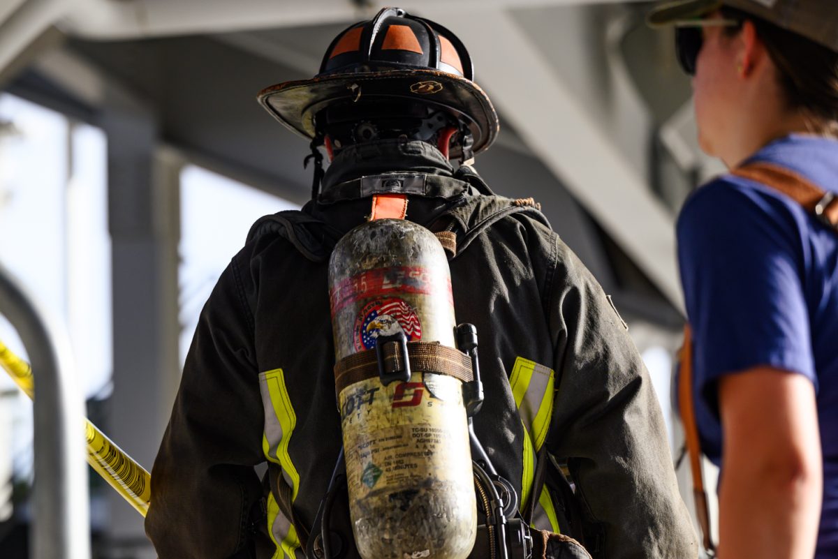 A firefighter in full gear with an oxygen tank strapped to his back walks away.