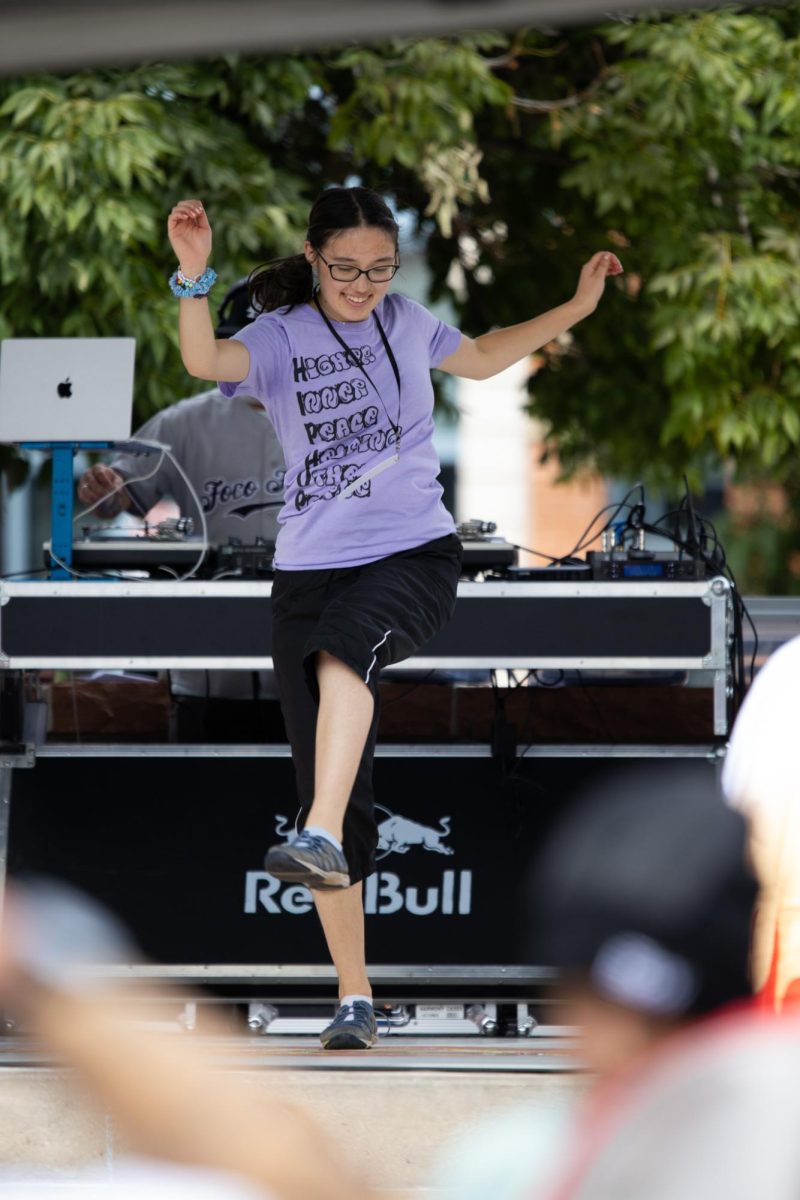 Young female dancer performing a hip-hop routine in front of a crowded square.