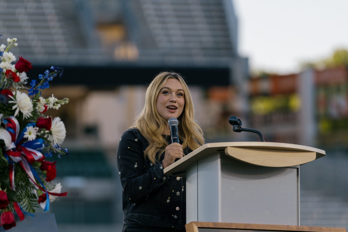 A women holding a microphone speaks at a podium.