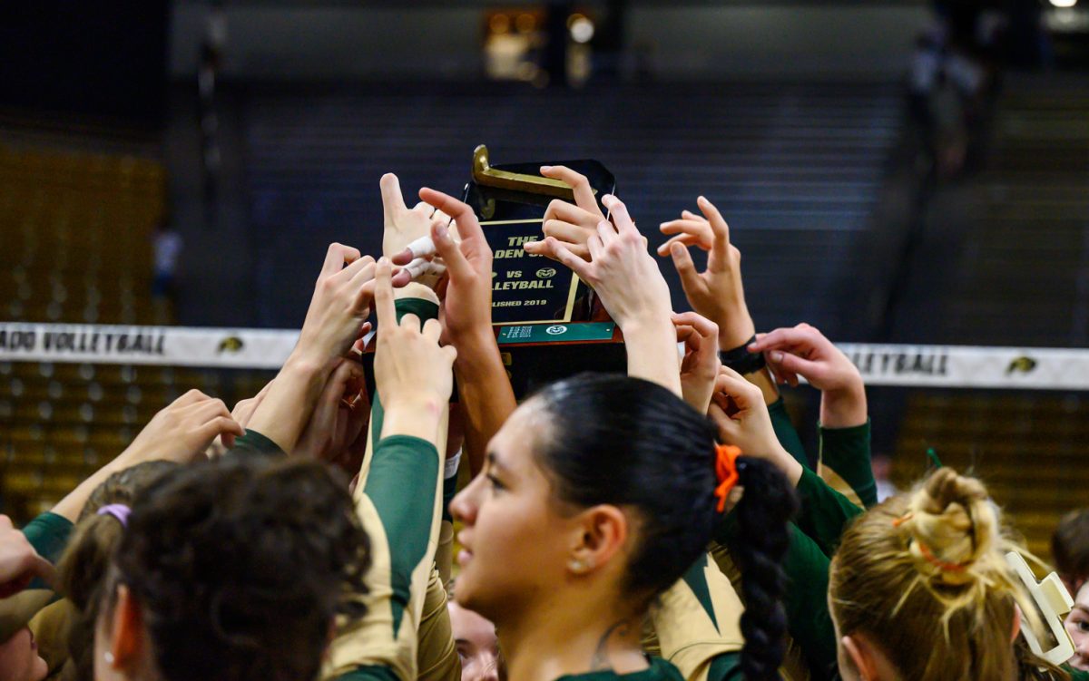Colorado State University's volleyball team holds up ram signs and the Golden Spike trophy after their second game against the University of Colorado Sept. 19. CSU won 3-1.