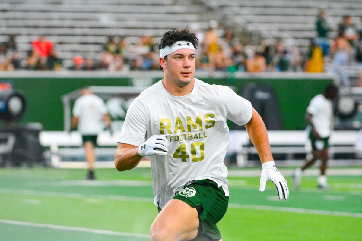 Football player in a white shirt with gold letters running.