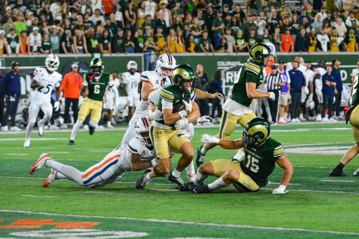 Football player in a green and gold jersey getting tackled by a player in a white jersey.