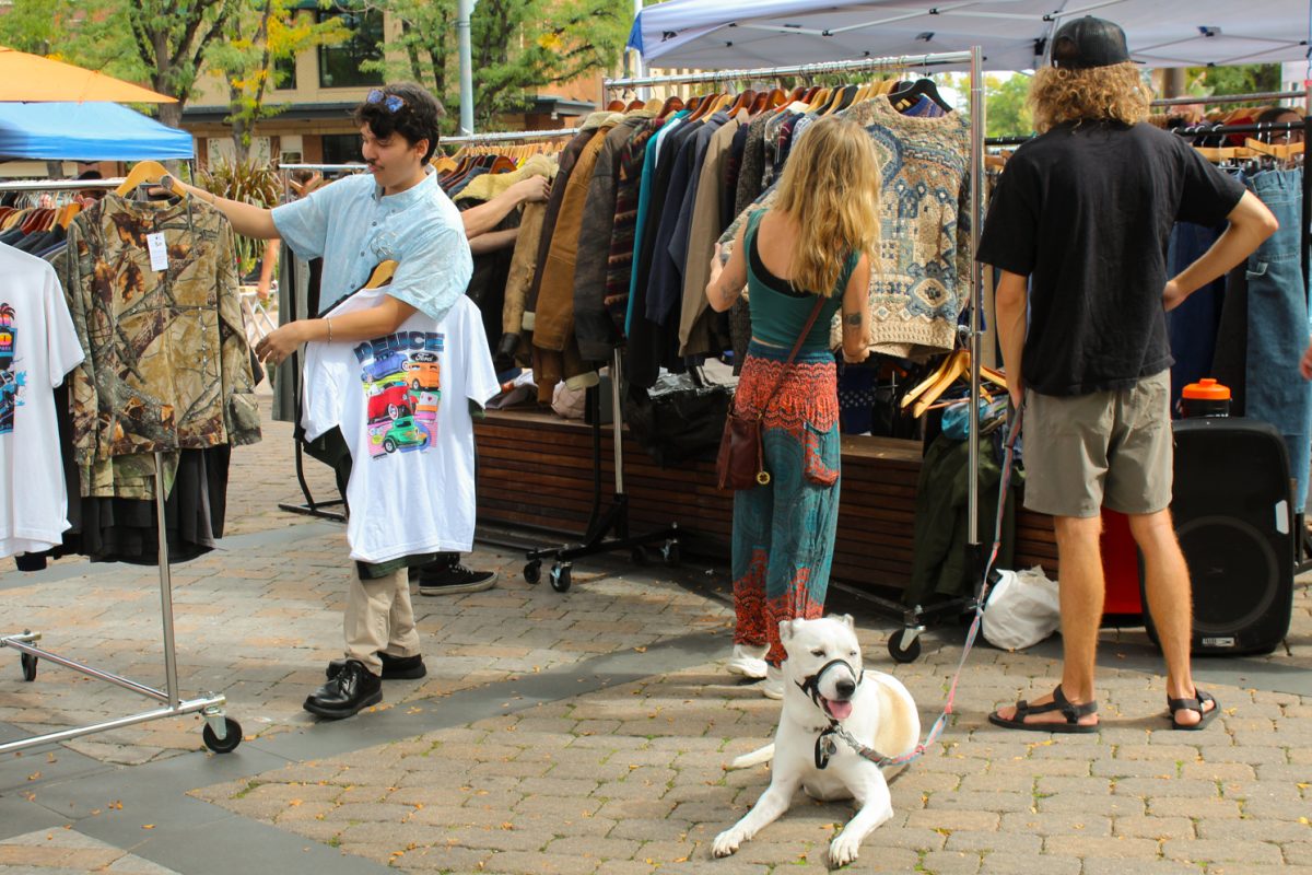 Local passersby wander near and browse Fort Collins Vintage Market clothing booths set up along South College Ave on the Oak Street Plaza Sept. 20.