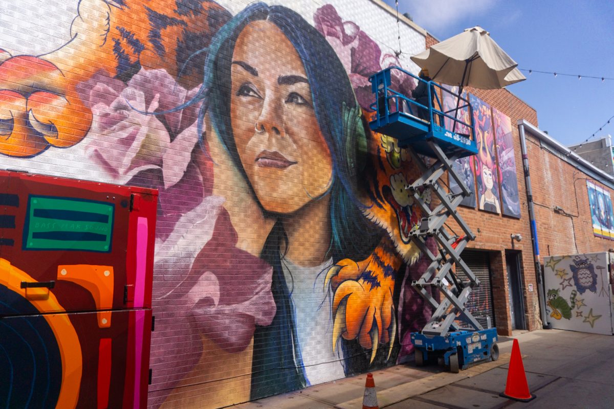Chelsea Lewinski adds details to her mural during WeldWalls Mural Festival in Greeley Sept 20. The mural, "Basslines Bloom" is meant to be a visual song according to the mural description. "The bassline (the tiger) represents depth, darkness and the weight we all carry," Lewinski explained.