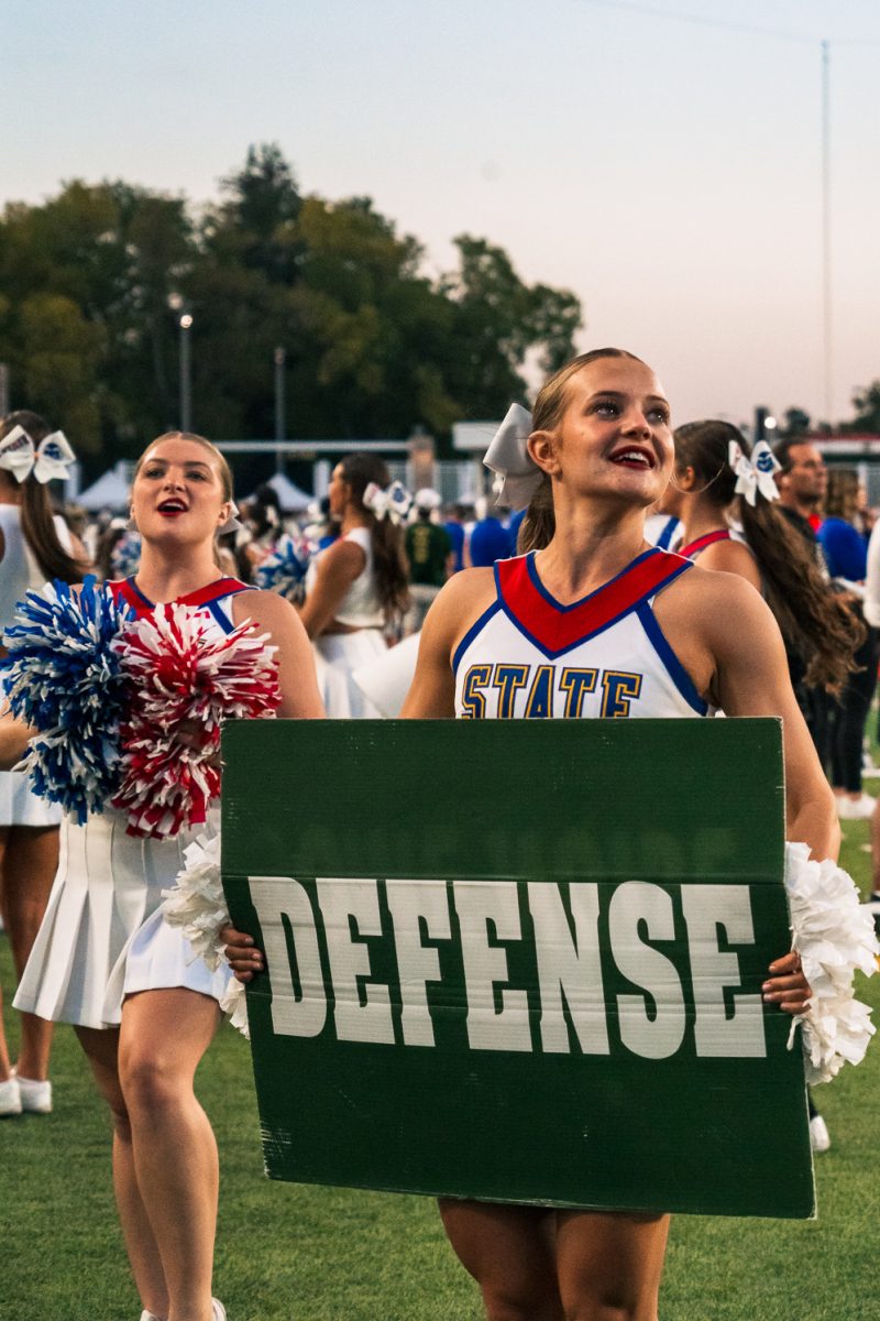 Colorado State University cheerleader Bridget Hauger holds a sign reading "DEFENSE" to the crowd during the second quarter as the Rams took on Washington State Sept. 27. The game was CSU's annual football State Pride game.