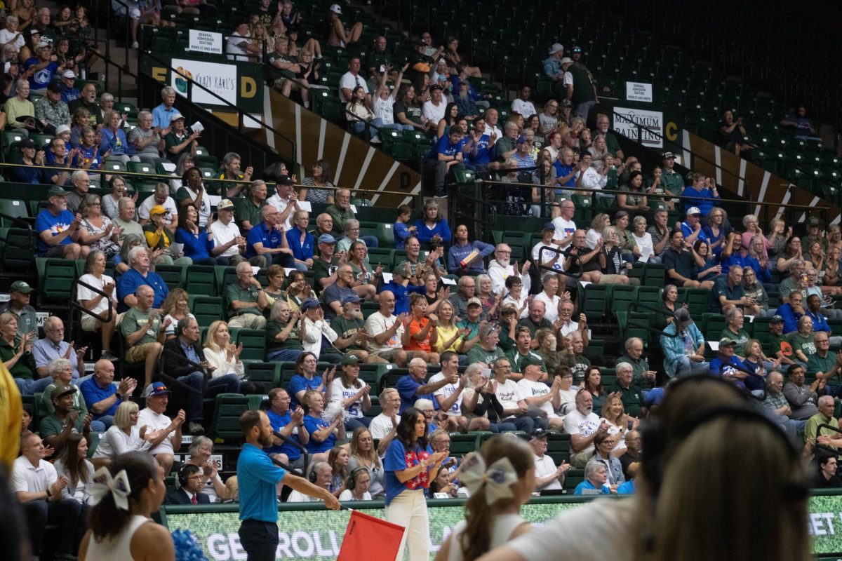A crowd of people clapping their hands together with smiles on their faces.