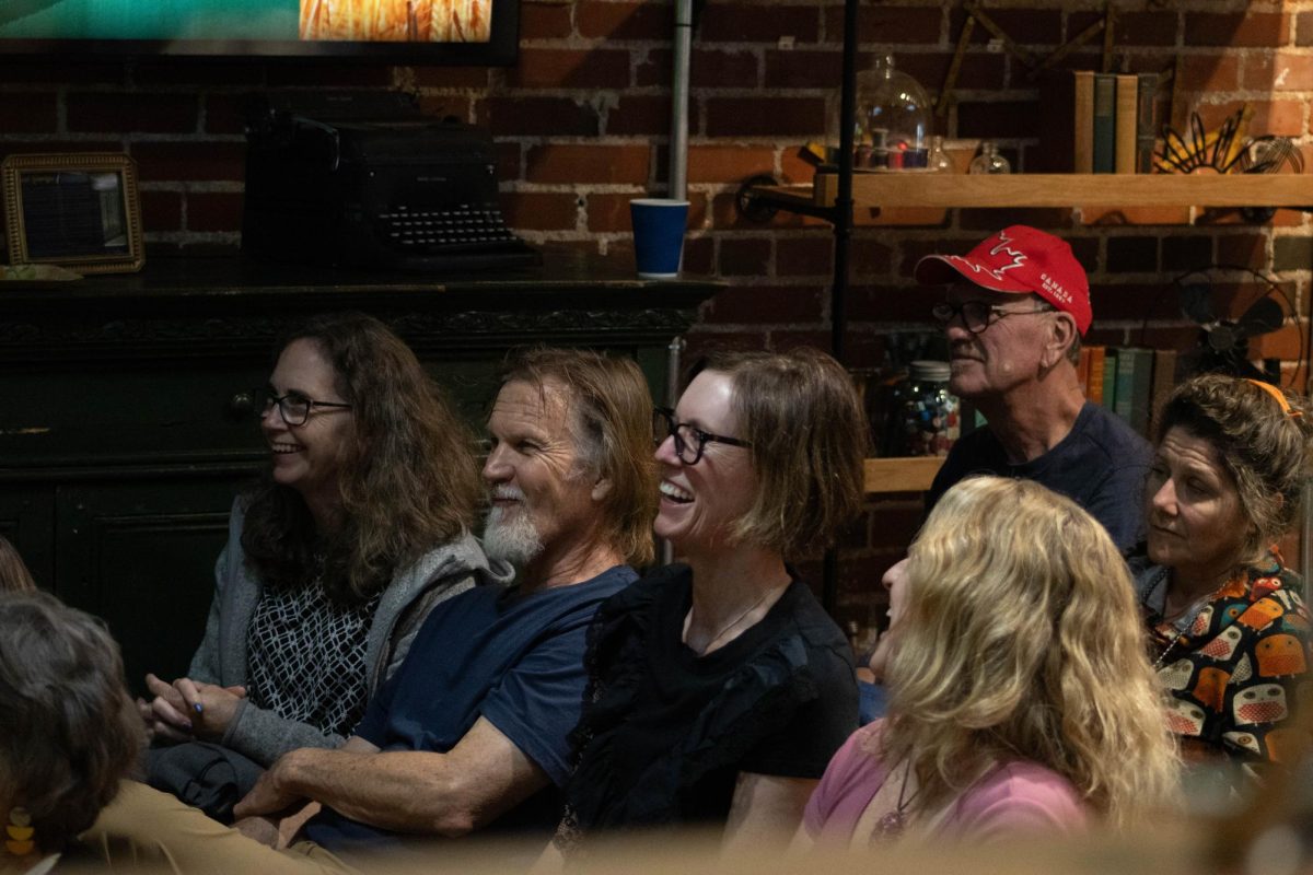 Two older women, and an older men with a grey beard laughing with smiles on their faces. The two women are wearing glasses and the man is wearing a blue t-shirt.