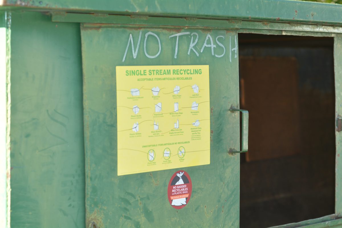 A green recycling container with a yellow instruction manual