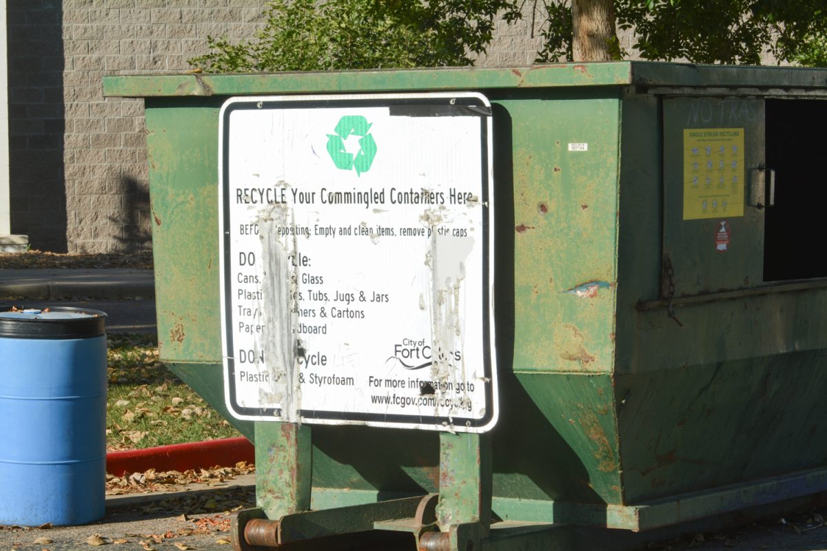 A green recycling container with a white sign on it.