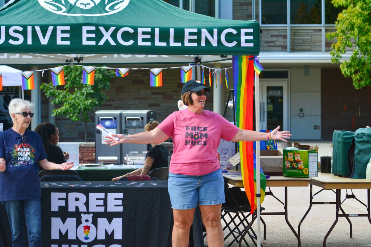 A woman in a pink shirt with her arms spread wide.