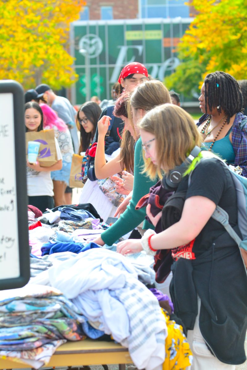 A group of people sifting through a pile of clothes.