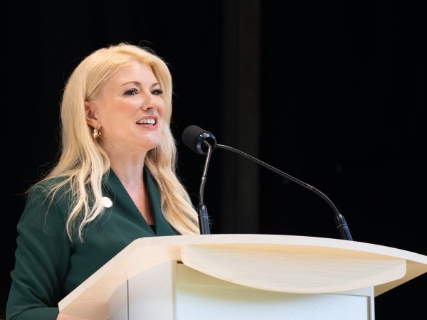 A woman gives a speech at a podium.