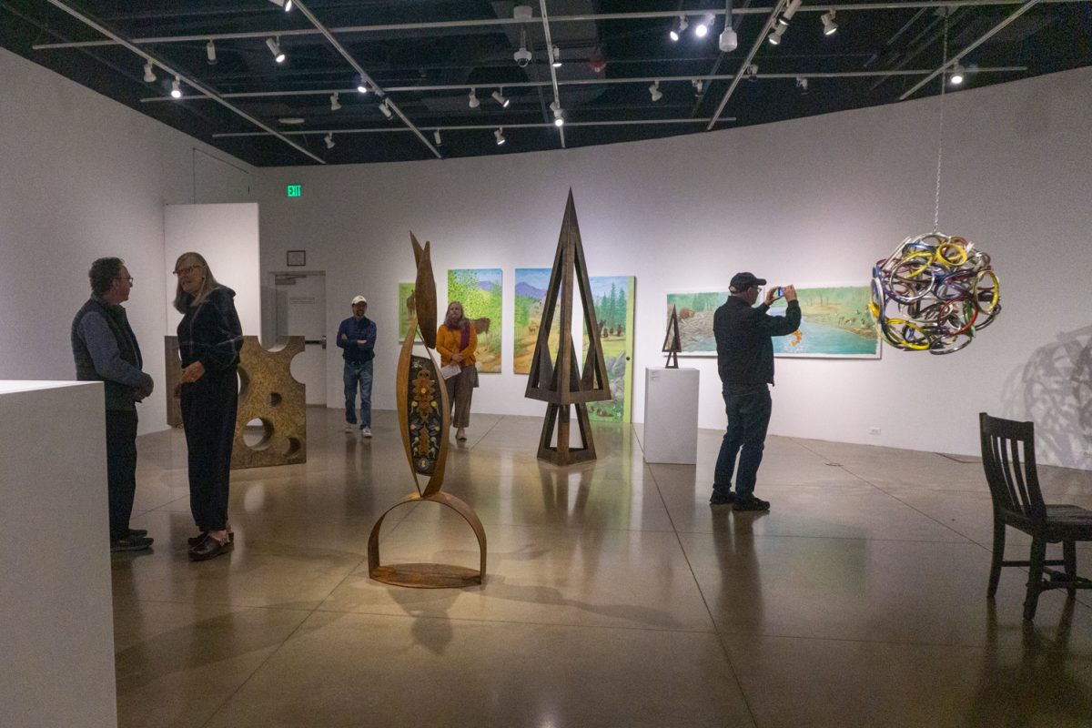 Guests view and photograph various pieces of art in the Lincoln Center Gallery Oct 10. The art gallery showcases the personal artwork of six artists who are creating art to enrich local public spaces.