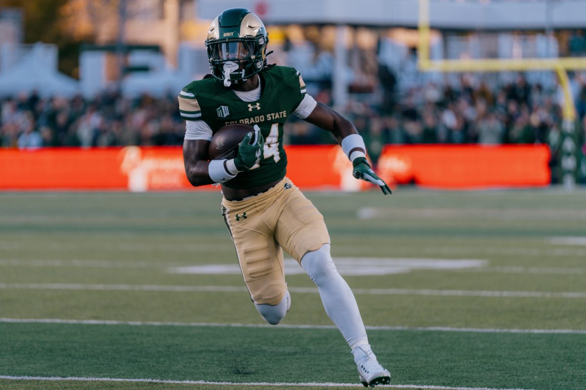 A football player runs down the field with the ball.