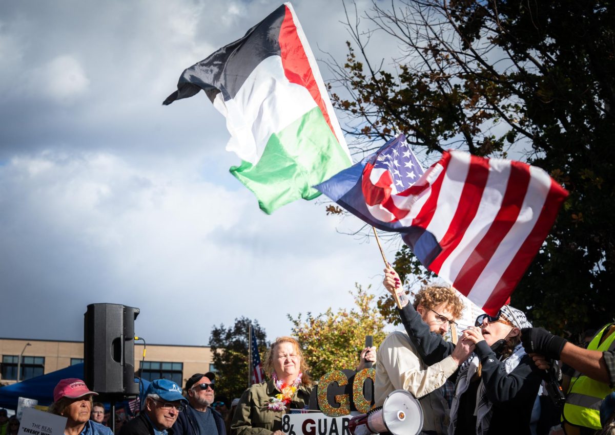 A woman waves the Palestinian flag and speaks into a megaphone.