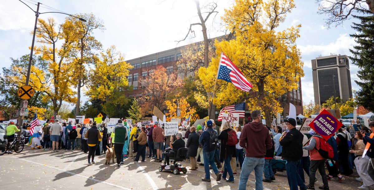 Protesters with signs and flags walk down a street below an upside down American flag.