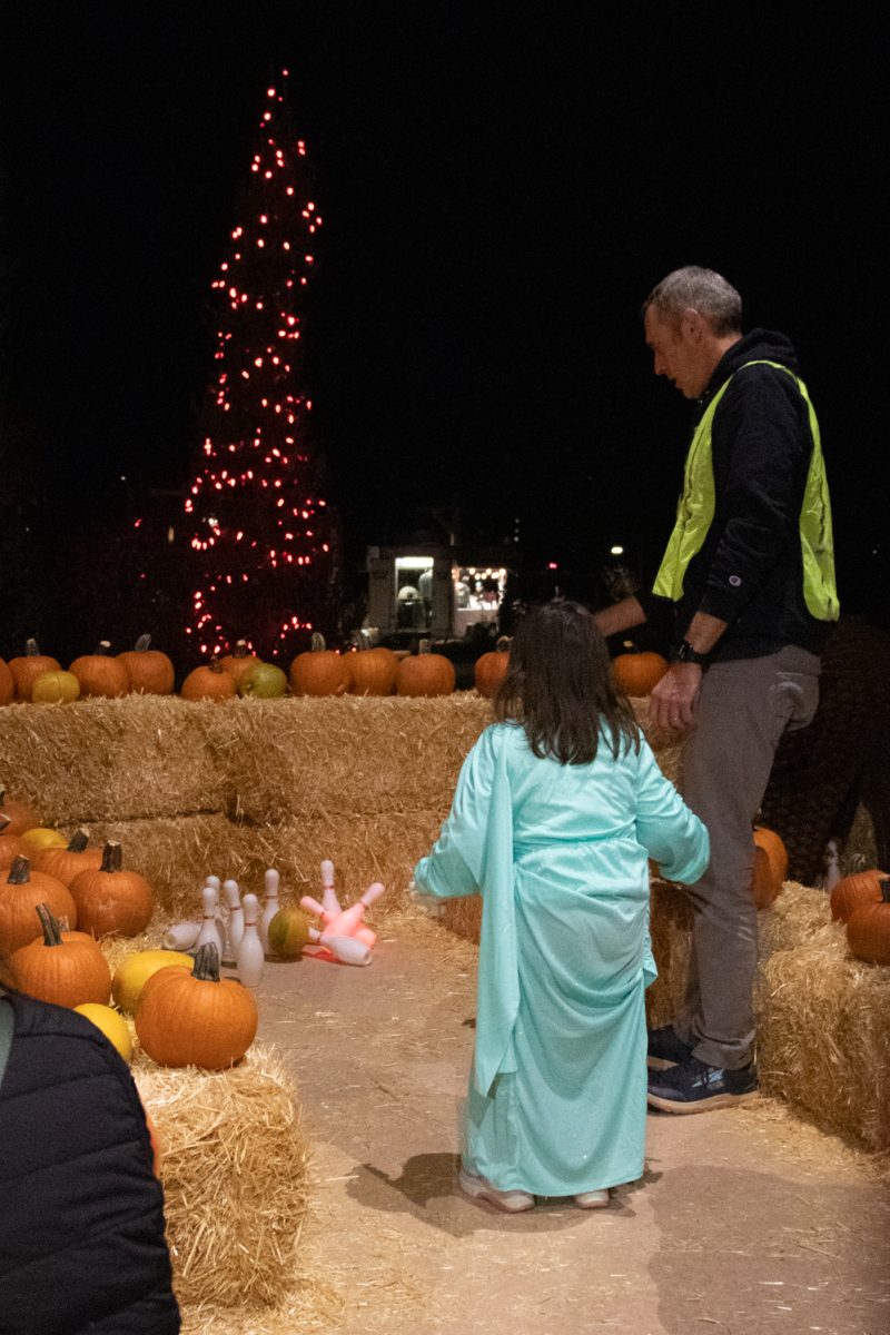 A child rolls a pumpkin at bowling pins during Pumpkins on Parade at the Gardens on Spring Creek Oct 24.