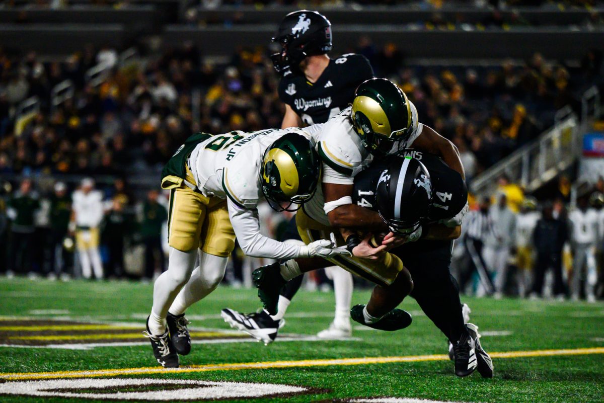 Colorado State University football defensive back Chance Harrison (16) and linebacker Jaseim Mitchell (23) take down University of Wyoming quarterback Landon Sims (14) during CSU's game in the War Memorial Stadium Oct. 25.