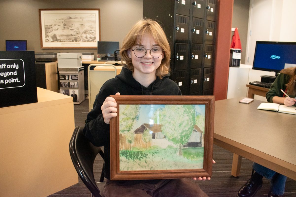 Front Range Community College Student Emilee Askeland smiles for a photo holding her aunt’s watercolor painting while participating in the Colorado State University student-led archiving project at the Museum of Discovery Oct. 25. “This is a painting of the house my mom and aunt grew up in,” said Askeland.