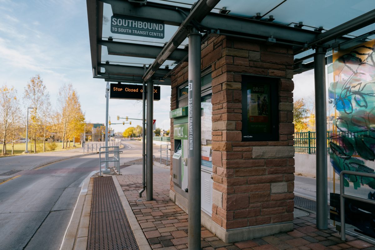 A bus stop with brick pillars and a glass cover.