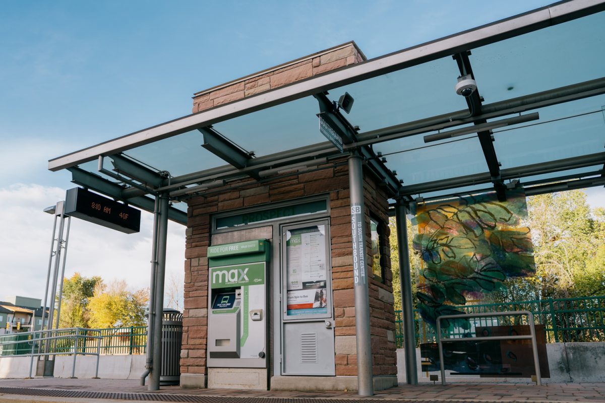 A bus stop with brick pillars and a glass cover.