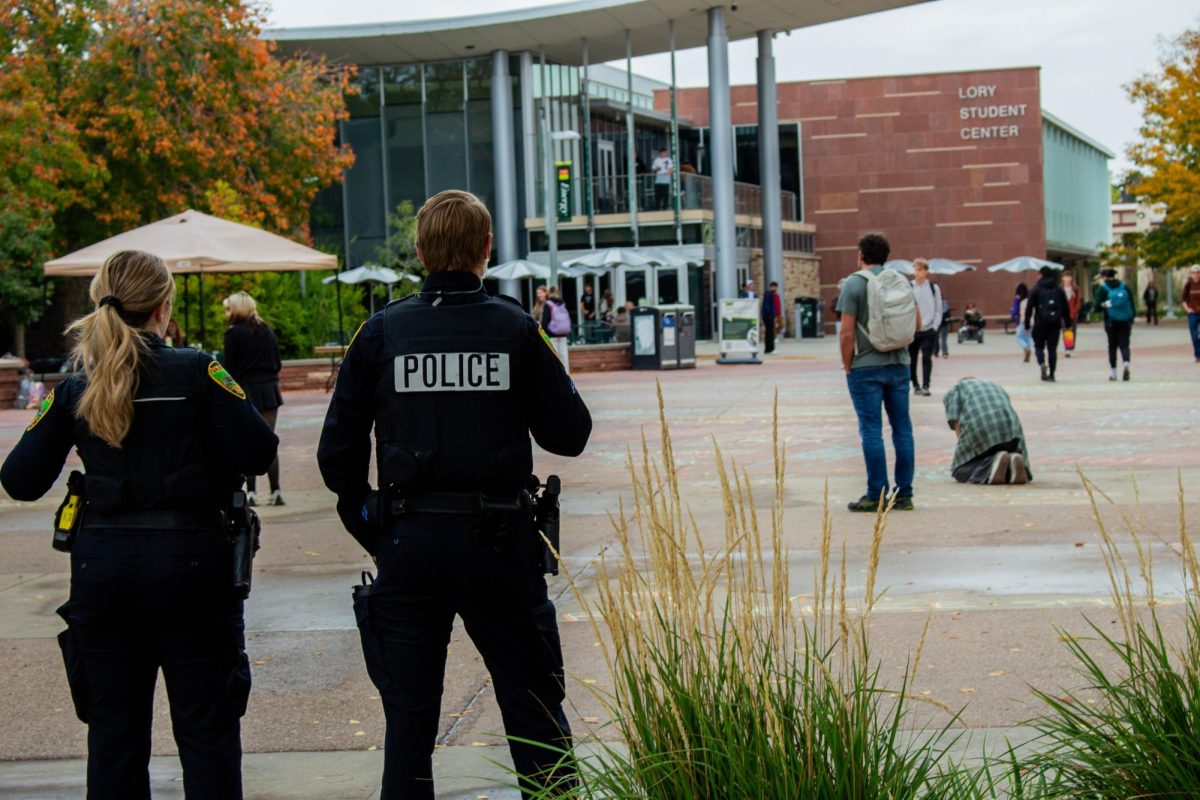 Colorado State University Police Department offices watch students chalk messages on The Plaza Oct. 7. Chalk messages were erased per a 2025 free speech policy update. 