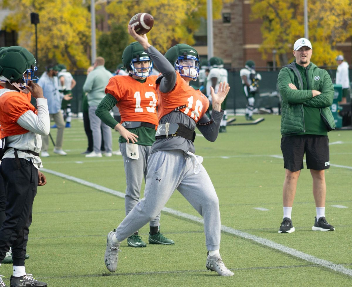 A player in an orange jersey and grey sweatpants has the ball in his right hand, his hand is above his head moving forward.