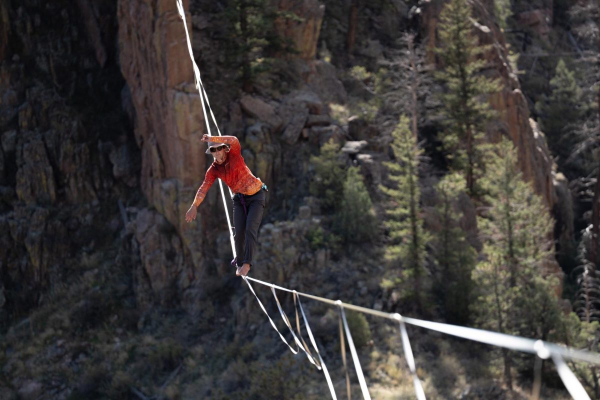 A person walks on a highline suspended between two towers.