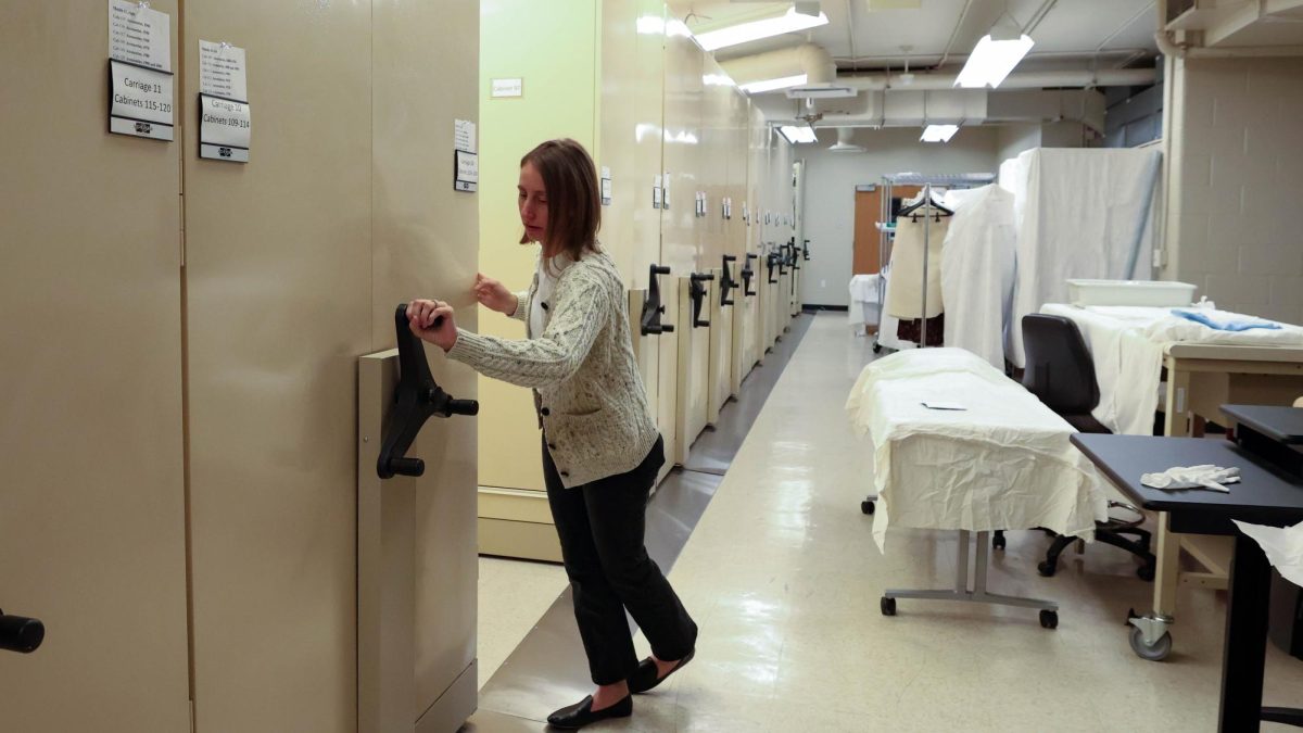 Interim Director of the Avenir Museum, Megan Osborne, rolls a carriage of garments and textiles down the row, allowing access to the other carriages in the collection. The Avenir holds 11 of the carriages, and within them, a total of 143 cabinets full of textiles and apparel, Oct. 6.
