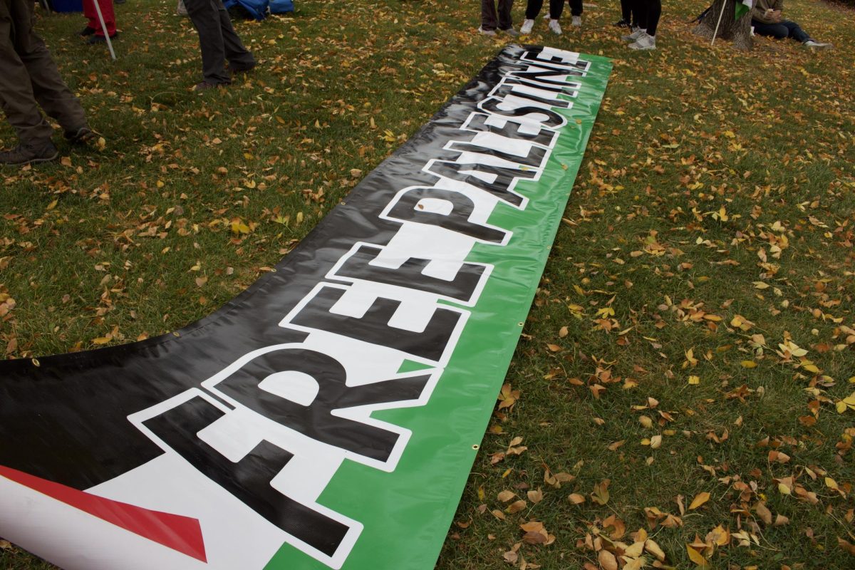 A banner that reads "Free Palestine" is displayed on the Walmart lawn at Harmony and College where community members rest after marching the first 5 miles of a 14 mile march meant to simulate a walk to Al-Mawasi in Gaza Oct. 11.