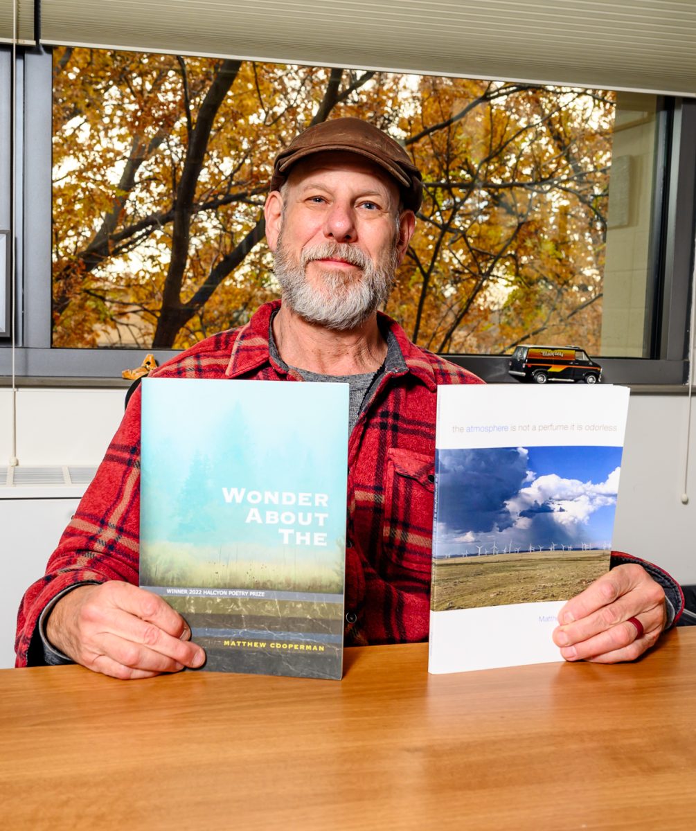 Colorado State University professor and author Matthew Cooperman poses for a portrait with his published books in his office Nov. 3.