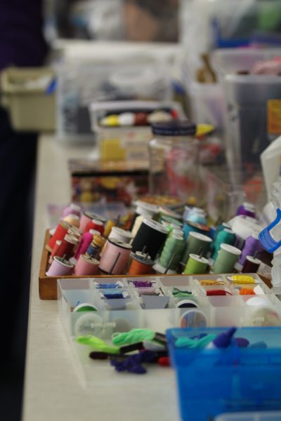 A counter is cluttered with thread of every color, embroidery floss, and jars of buttons.