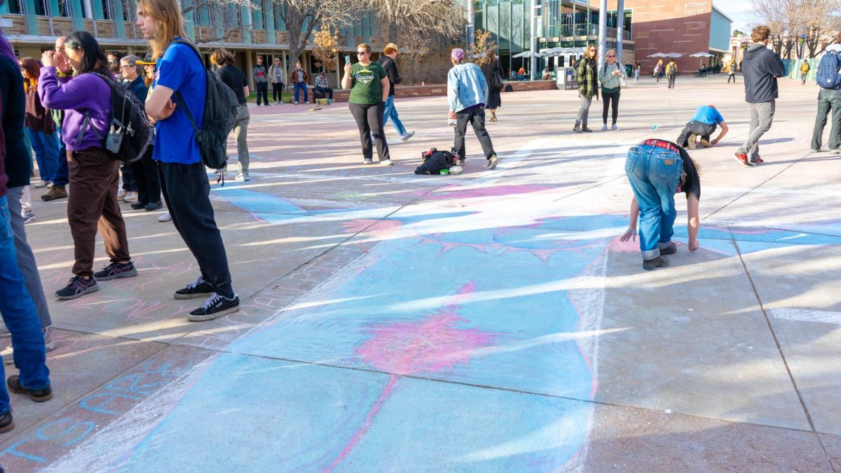 A student protestor chalks an image of a transgender Jesus on a pre-existing cross drawing on The Plaza Nov. 19 as part of the Student Mass Assembly hosted by The United Front. The assembly included discussion around transgender messaging at Colorado State University and free speech rights on The Plaza. 