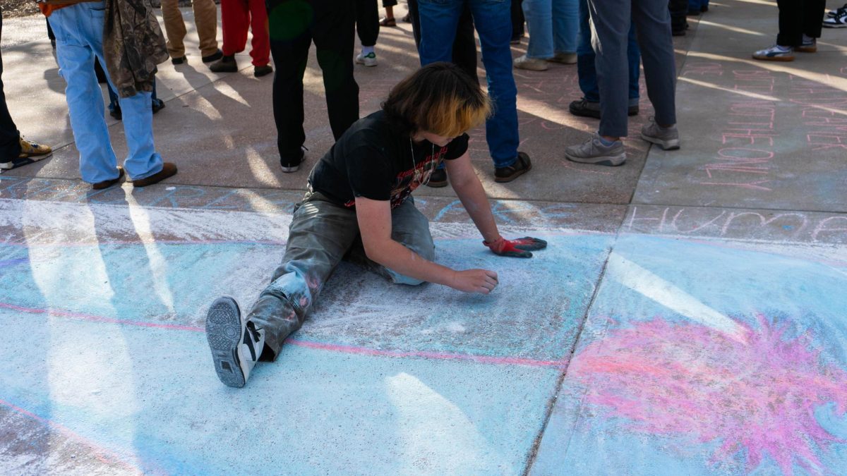 A student protestor chalks an image of a transgender Jesus on a pre-existing cross drawing on The Plaza Nov. 19 as part of the Student Mass Assembly hosted by The United Front. The assembly included discussion around transgender messaging at Colorado State University and free speech rights on The Plaza. 