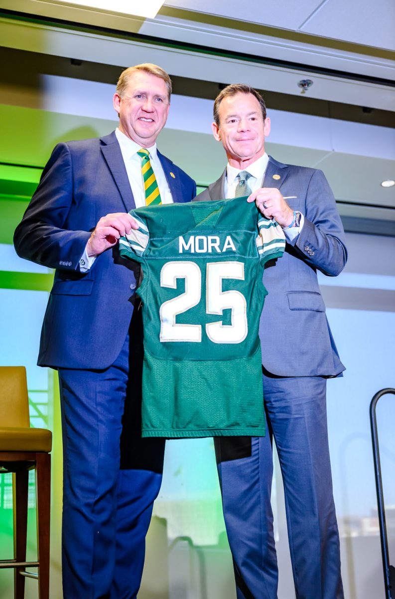 Director of Athletics John Weber and head football coach Jim Mora hold up a Colorado State University football jersey with Mora's name after a press conference held in Canvas Stadium Dec. 1.