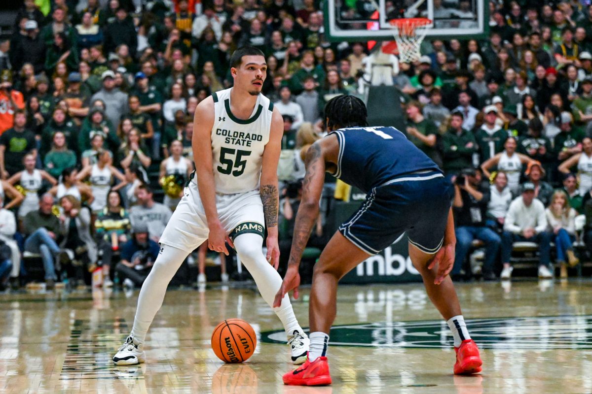 Colorado State University men's basketball guard Jevin Muniz (55) looks for a teammate to pass to while being pressured by Utah State University guard Elijah Perryman (1) Jan. 23.