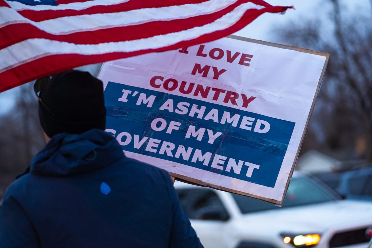 A protester holds up a sign and an American flag during a walkout Jan. 20. The walk-out was organized to protest federal policies and ICE activities across the country. The walkout was connected to similar events nationwide.