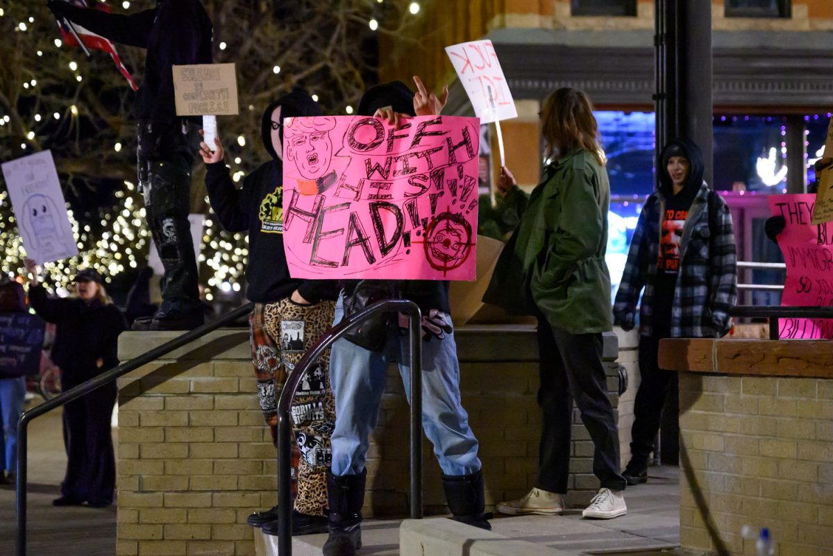 A protestor holds up a sign that reads, "Off with his head" and holds up a middle finger during an anti-ICE protest in Old Town Square Jan. 29.