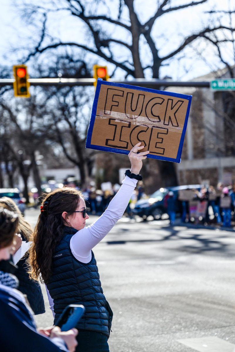 A protester displays their "Fuck ICE" sign to passing cars on College Avenue Jan. 30.