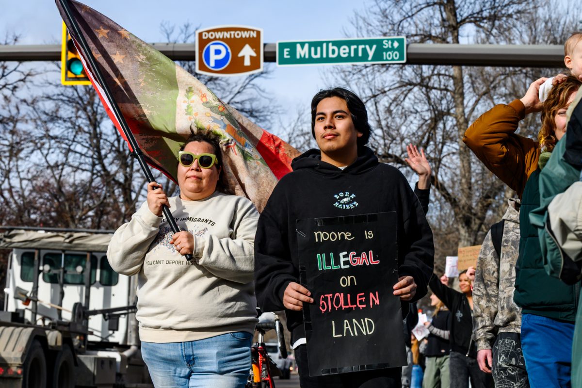 Protesters walk across Mulberry Street holding flags and signs to get the attention of passing cars during an anti-ICE protest Jan. 30.