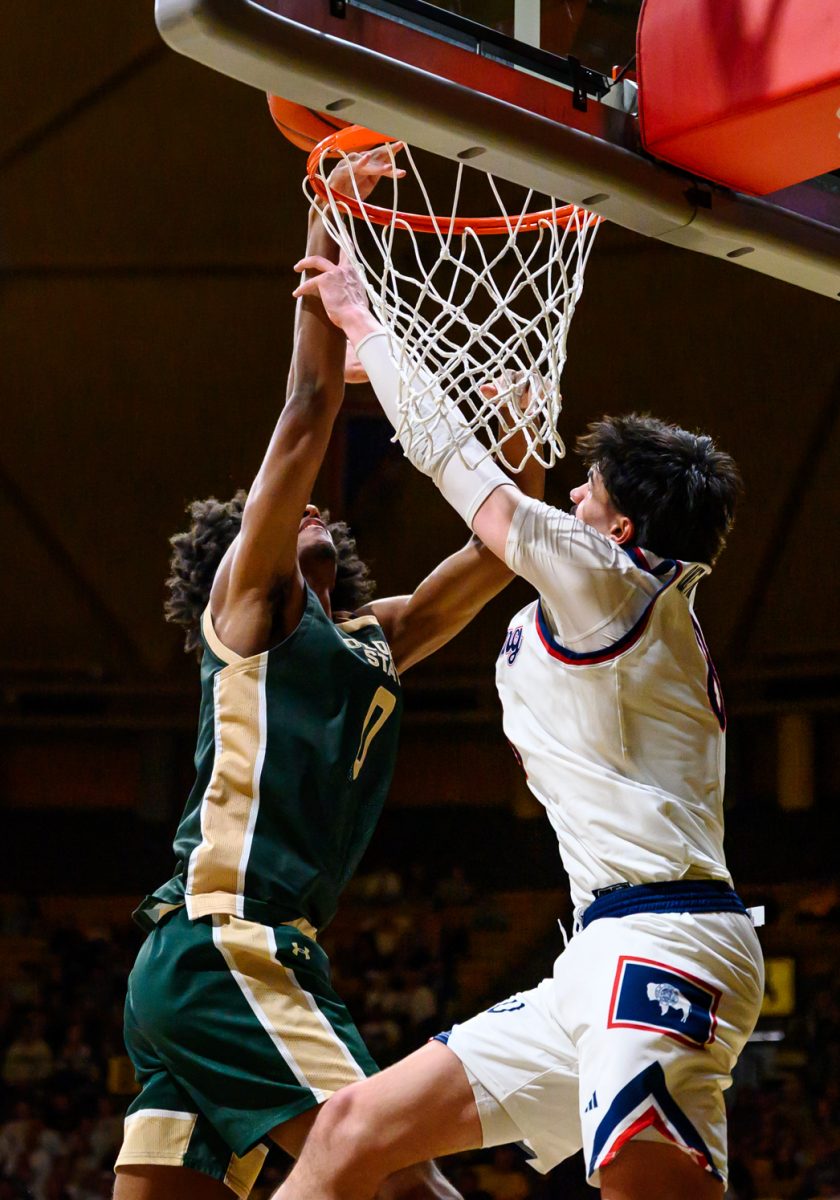 University of Wyoming forward Kiani Saxon (8) blocks Colorado State University men's basketball forward Carey Booth (0) from the net during CSU's game against UW Jan. 31. Booth scored four points during the game. 