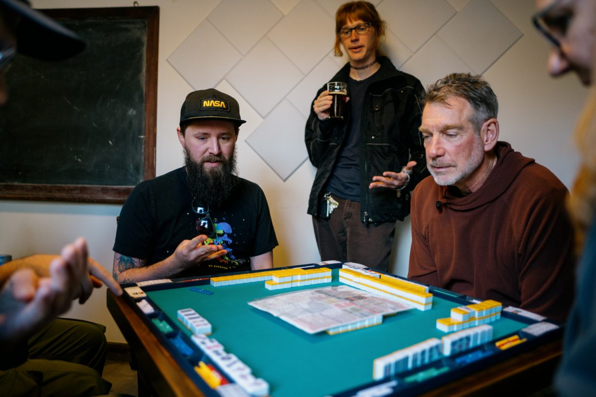 Jarrett McDowell, Avery Jackson and Todd Miklos study the discarded tiles during a game of riichi mahjong with Riichi NoCo at Stodgy Brewing Company Feb. 21. The riichi mahjong variant requires discarded tiles to be ordered, whereas with other mahjong styles, tiles are discarded into a pile.