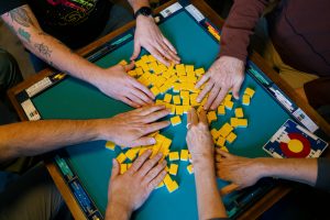 Players shuffle facedown Mahjong tiles with their hands.
