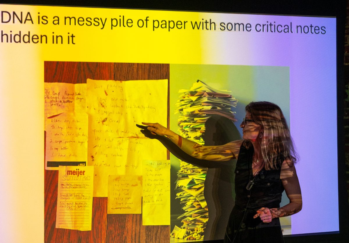 Dr. Rachel Mueller, an evolutionary biologist with a doctoral degree in integrative biology, discusses analogies used to describe DNA, and the varied shortcomings of each of them Feb. 25. Her favorite example, and the one that fits best she says, is a messy stack of papers. “DNA, to me, is a big, messy pile of paper with some critical notes or recipes hidden in it somewhere,” Mueller said. “That’s really what DNA is.”