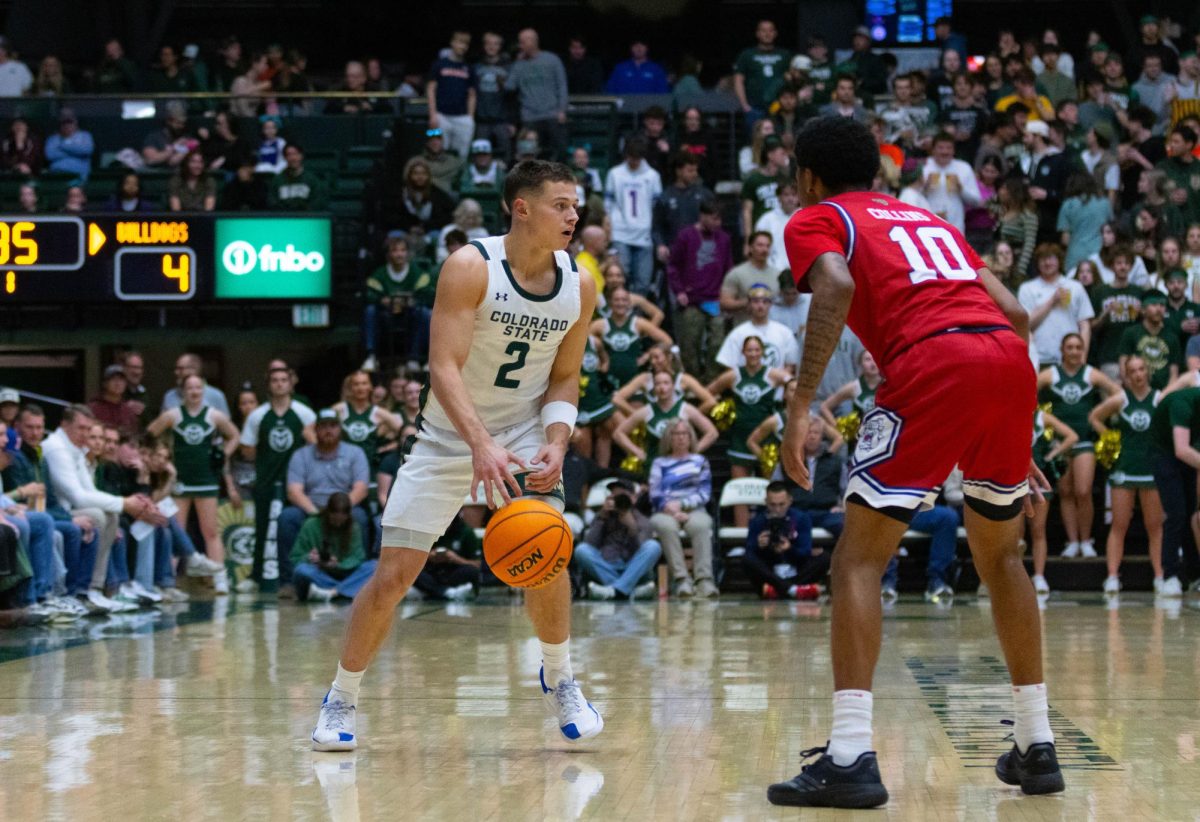 A man in an all white jersey dribbles the ball in front of a man in an all red jersey.