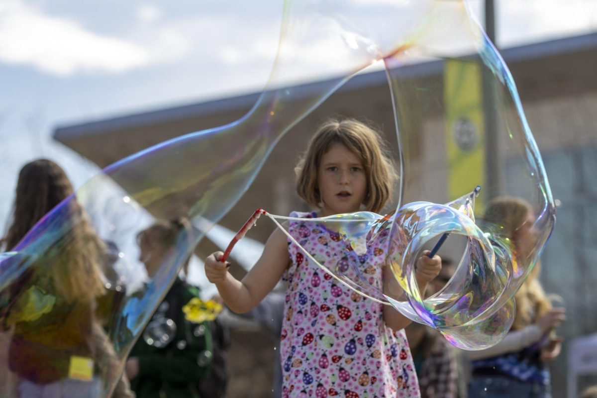 Scarlet, an attendee whose name was provided by a parent, uses giant wands and strings to create massive bubbles in the sun at the Little Shop of Physics Open House at the Lory Student Center March 1.