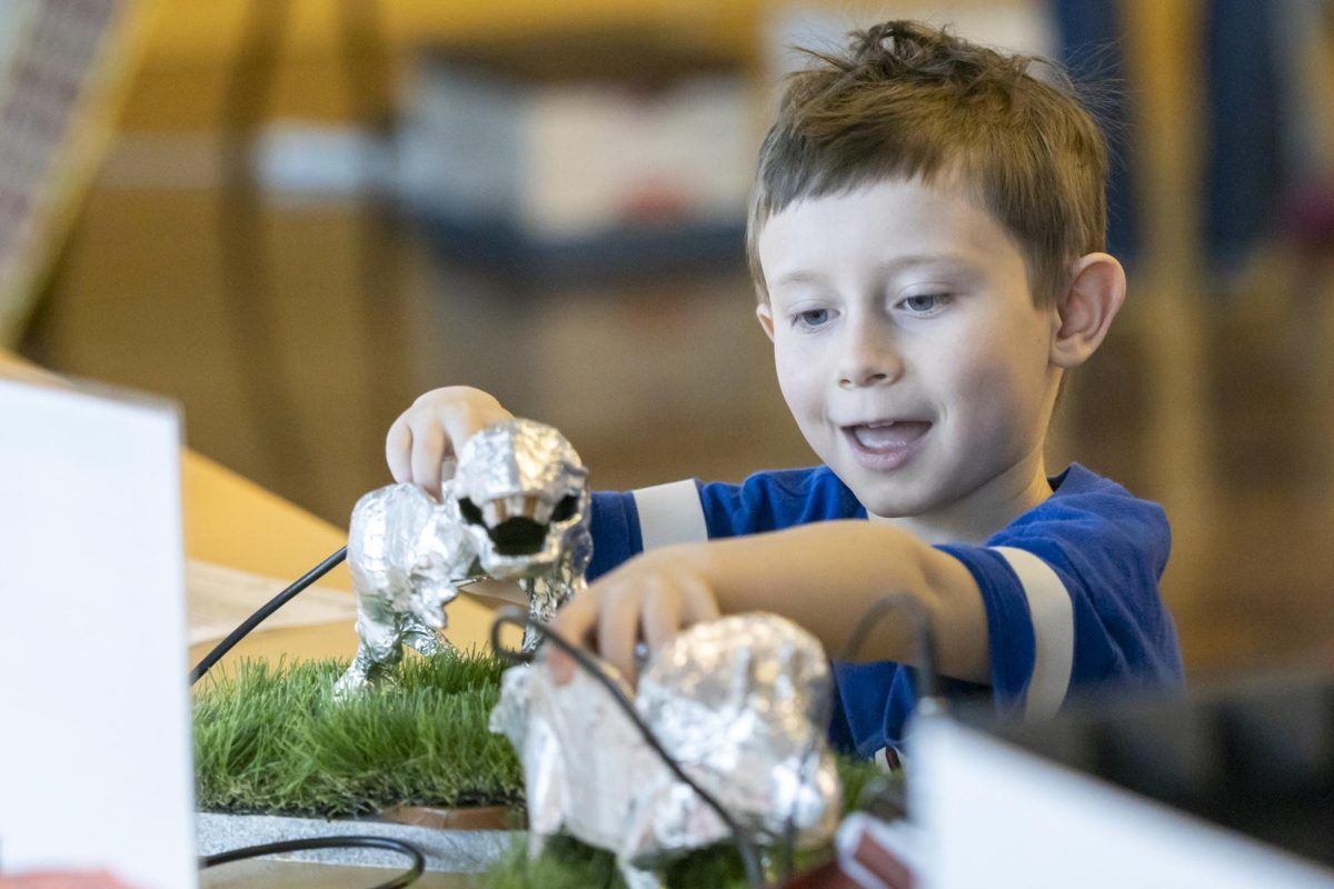 [Guardian gave permission, last name omitted] Nash creates a human circuit by touching two foil-covered dinosaurs at the Little Shop of Physics 32nd Open House March 1st.