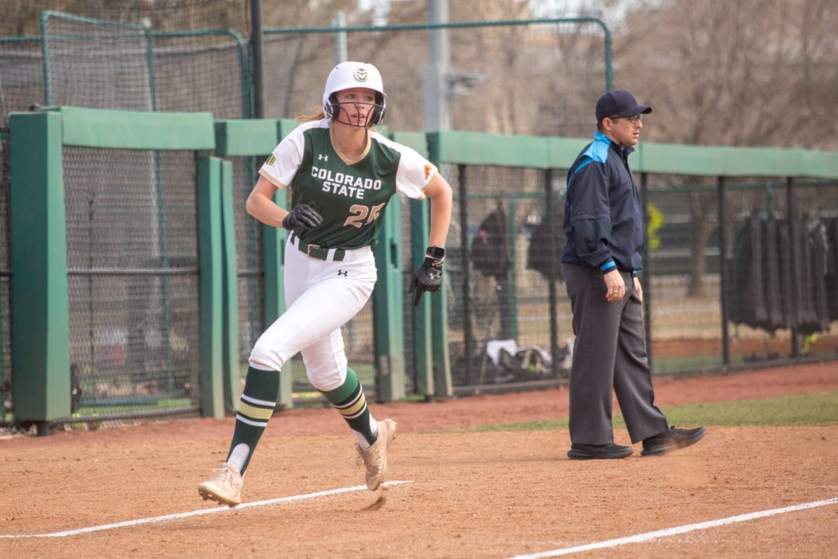 A girl in a white softball uniform runs.