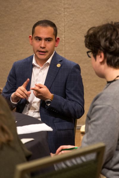 A large room with circle tables and people sitting at them.