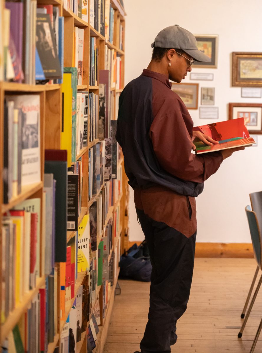 Phoon, a mononym, is a prominent member of the Gulo Gulo Poetry collective, looks for inspiration in one of the many books that line the room Mar. 3. A constant at these events Phoon takes them as a place for the community to come together. “Having that space means having a sense of solace and anchor or a North star depending on how they relate to the group,” Phoon said. “For some as an anchor, it can help keep them here, like with us, tethered alive. If it’s a North Star this place can be a space, this group can be a space for folk to look towards when they may lose their way, or if things get really dark and chaotic.”